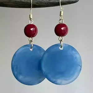 Vue détaillée de boucles d'oreilles vintage en acrylique bleu dépoli et perle rouge