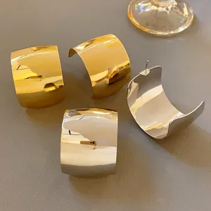 Vista dettagliata di grandi orecchini a cerchio a C color oro e argento con finitura lucida.