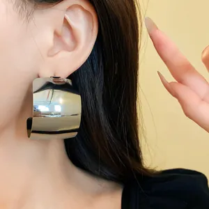 Primo piano di una modella con un ampio orecchino a C in metallo con finitura argento