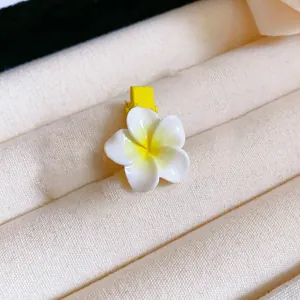 Close-up of a white and yellow plumeria flower hair clip for Korean summer hair styling.