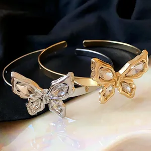 Detailed view of silver and gold butterfly cuff bracelets with sparkling crystals.