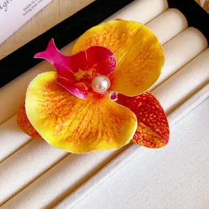 Detailed close-up of a vibrant yellow orchid flower hair clip with a white pearl