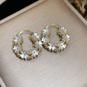 Primo piano di orecchini a cerchio placcati oro 14K con eleganti fiori in stile madreperla