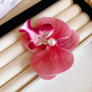 Close-up detail of a vibrant pink orchid flower hair clip with a decorative white pearl