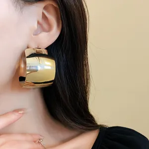 Primo piano di eleganti orecchini a cerchio quadrati a forma di C dorati su modella