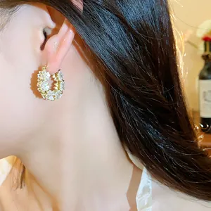 Vista dettagliata di eleganti orecchini a cerchio con fiori e perle placcati oro 14K.
