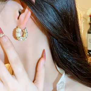 Primo piano di eleganti orecchini placcati oro 14K con fiori bianchi e piccole perle
