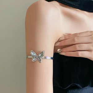 Close-up detail of sparkling rhinestone butterfly open arm cuff bracelet on woman's upper arm