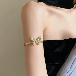 Detailed view of an elegant gold rhinestone butterfly armlet worn on the model's upper arm