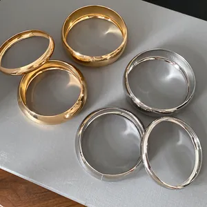 Detailed view of polished geometric metal bangles in shiny gold and silver finishes