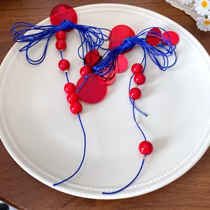 Detail view of retro red and blue bow knot tassel earrings with beads on a white plate