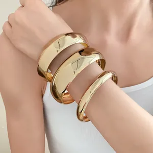 Close-up of glossy gold chunky metal bangles worn on arm for a high-end fashion look