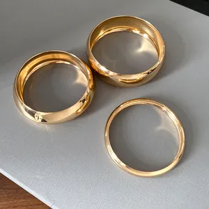 Close-up of three polished gold metallic bangles showing smooth geometric finish