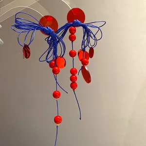 Detailed view of red and blue bow tassel earrings with acrylic discs and bead accents