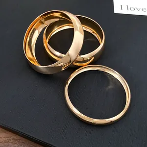 Close-up macro shot of three gold metallic smooth bangles resting on a textured black surface