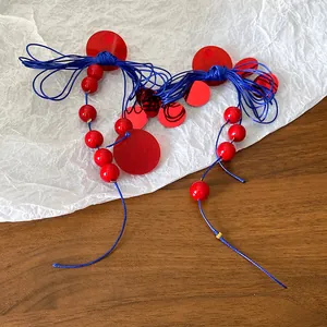 Detailed view of retro red and blue bow tassel earrings on textured background.