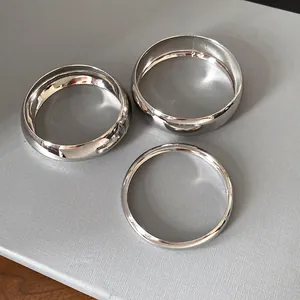 Top view of three minimalist polished silver metal bangles with different band widths