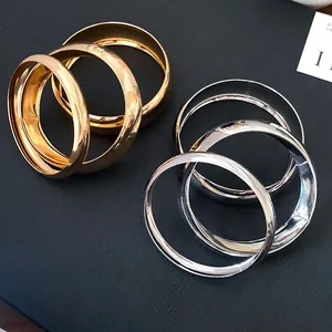 Detailed view of wide metallic geometric bangles with high-polished gold and silver finishes.