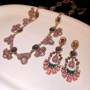 Vintage resin rhinestone flower necklace and earrings set on white ceramic tray