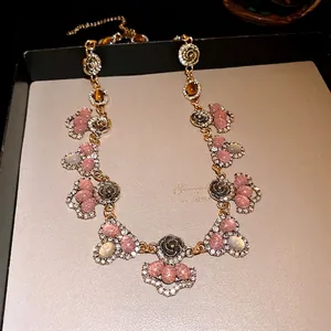 Vintage floral resin necklace with rhinestone accents on elegant jewelry display tray.
