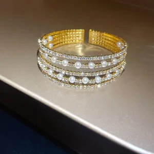 Detail view of an elegant multi-layer open cuff bracelet adorned with pearls and rhinestones.