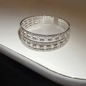 Close-up of multi-layer silver bangle with sparkling rhinestones and white pearls