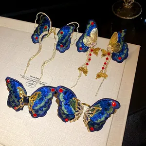 Detailed shot of embroidered butterfly tassel earrings with blue wings and gold accents