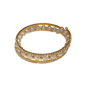 Elegante bracciale avvolgente a tre strati con perle bianche e strass scintillanti in oro.