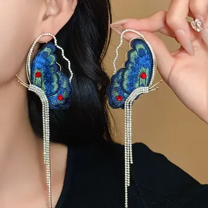 Detailed view of long butterfly tassel earrings with blue embroidery and rhinestones