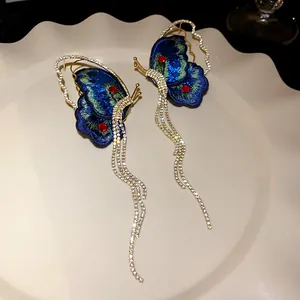 Detailed shot of elegant butterfly tassel earrings with blue embroidery and rhinestones