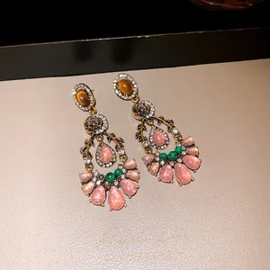 Close-up of vintage resin drop earrings with pink stones and floral metal design