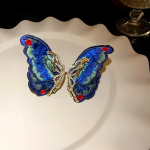 Detailed view of an exquisite embroidered butterfly earring with crystals and red gems
