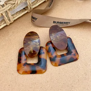 Detailed view of tortoiseshell resin geometric square and oval drop earrings.