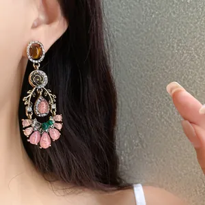 Close-up of vintage floral dangling earrings with pink resin and shiny rhinestones