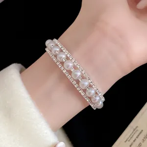 Dettaglio di un elegante bracciale a tre strati con perle e strass indossato al polso