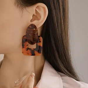 Close-up of vintage tortoiseshell resin earrings with geometric square and oval design