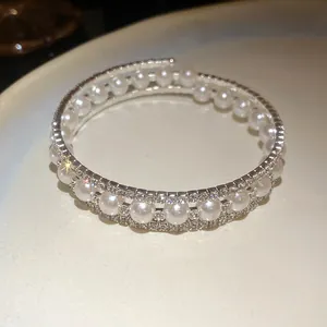 Vista dettagliata del bracciale a tre strati avvolgente con perle e strass luccicanti.