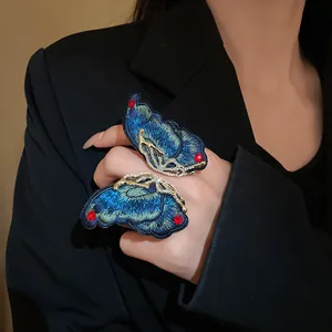 Detailed view of an elegant blue embroidered butterfly statement ring with gold crystals