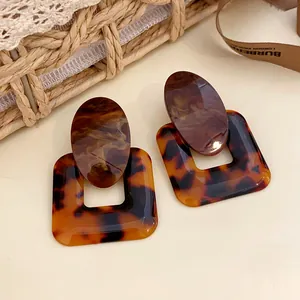 Macro view of vintage tortoiseshell resin earrings with oval and square geometric designs.