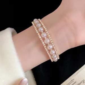 Dettaglio ravvicinato di un lussuoso bracciale a tre strati con perle bianche e strass.