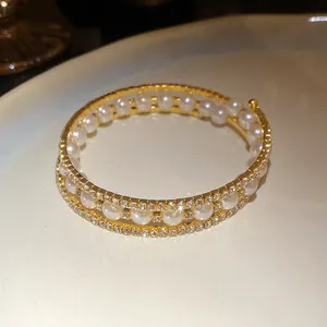 Vista macro dettagliata dell'elegante bracciale aperto a tre strati con perle e strass.