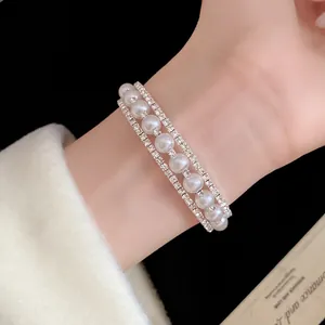 Elegante bracciale a tre file con perle e strass luccicanti indossato al polso