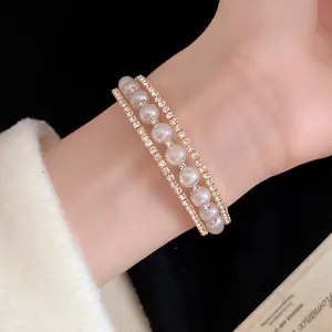 Primo piano dettagliato di un elegante bracciale in oro a tre strati con perle e strass