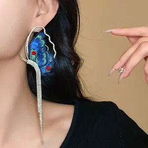 Exquisite close-up of blue embroidered butterfly tassel earrings with rhinestones on a model