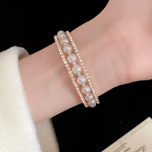 Primo piano di un elegante bracciale a tre strati in oro con perle e strass al polso