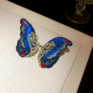 Detailed view of luxury blue embroidered butterfly earring with gold rhinestones