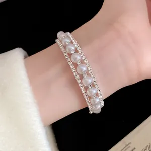 Elegante bracciale a tre strati con perle bianche e strass scintillanti sul polso