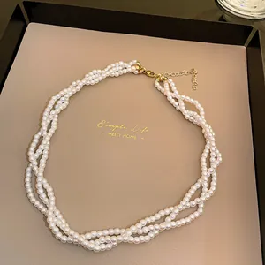 Elegant multi-layer twisted white pearl necklace displayed on a beige jewelry tray