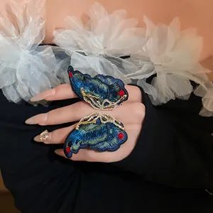 Detailed view of embroidered blue butterfly earrings with gold frame and crystals