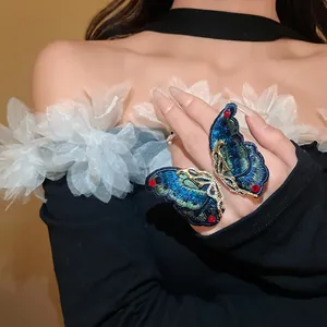 Detailed view of an exquisite embroidered butterfly ring with vibrant red gemstone accents.